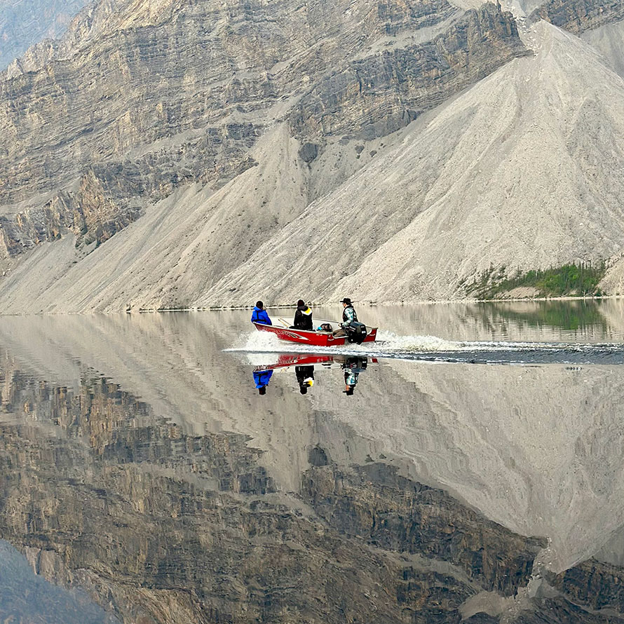 A group canoeing on a lake in front of a mountain