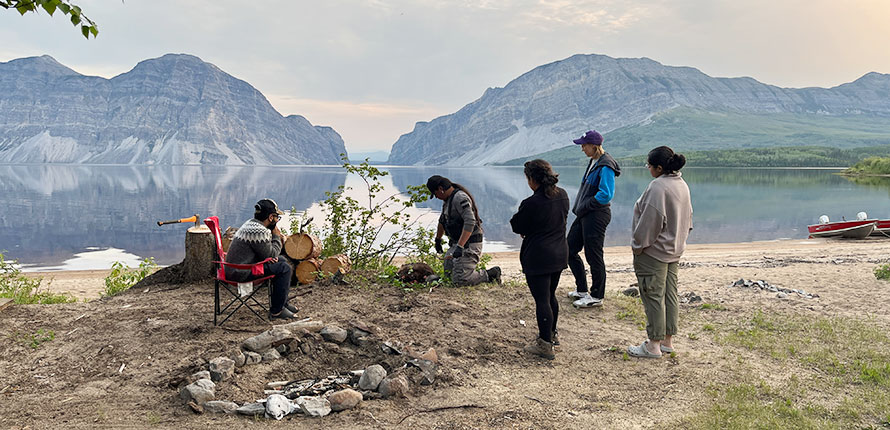 Kate Cain and others gathered around in front of a lake in the Northwest Territories