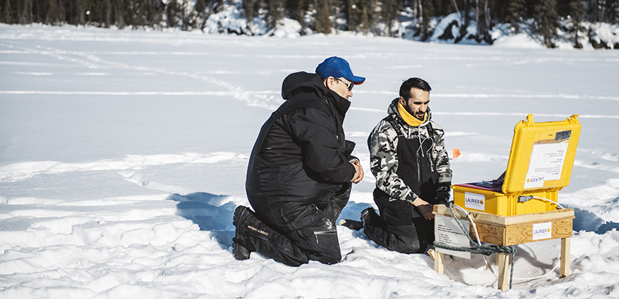 Chase Lockhart and Arash Rafat handling a lake ice sensor system.