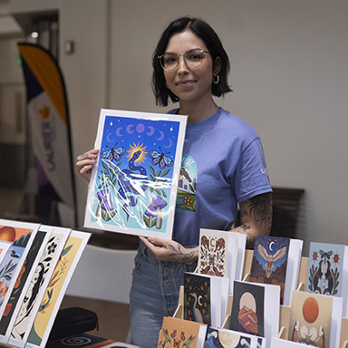 Artist Alanah Jewell holds up one of her art prints